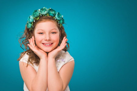 Girl with flower decorations. White dress. Turquoise background.の写真素材