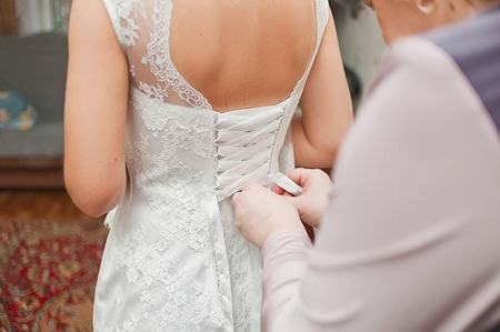 bridesmaid tying bow on wedding dressの写真素材