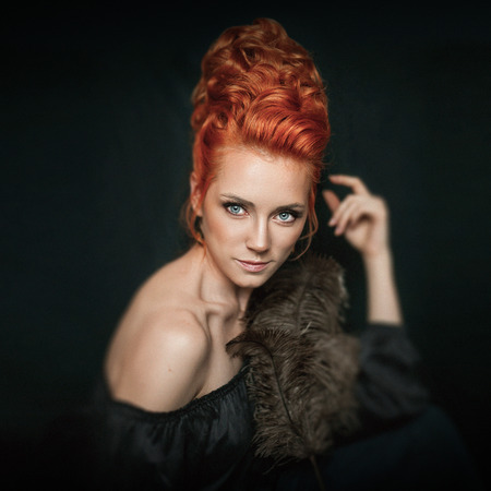 Portrait of redhead woman with blue eyes wearing black dress on dark background.の写真素材
