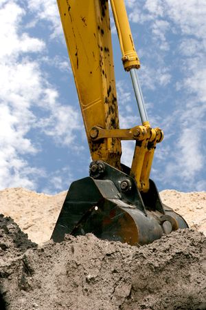 A back hoe digging in piles of dirt.の写真素材