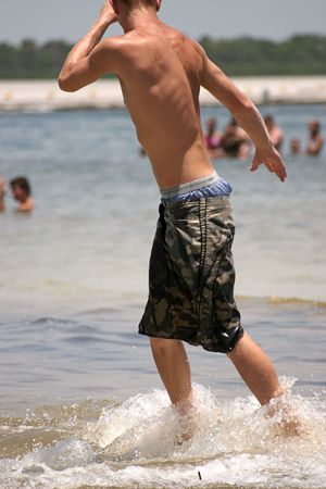 A very attractive young man with a tan and muscles skimboarding at the beachの写真素材