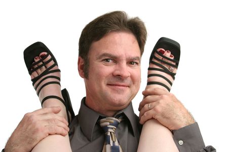 A smiling man in business clothes with a woman's feet on his shoulders.の写真素材