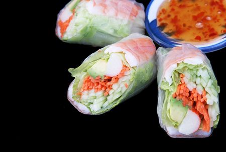 A salad roll with chili sauce on a black background with room for textの写真素材