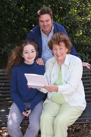 A father, daughter and grandmother reading good news together.