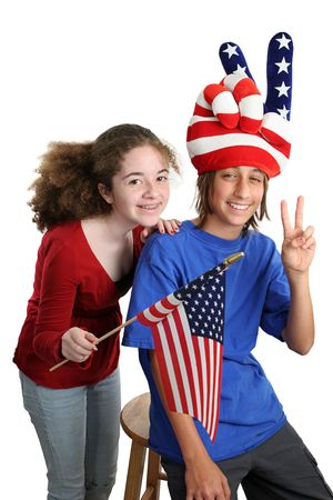 Two teens celebrating American Independence Day with patriotic hat and US flag.  Isolated.の写真素材