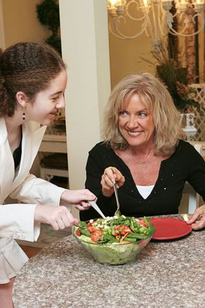 A woman and a teen digging in to a healthy salad for lunch.の写真素材