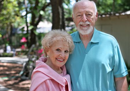 An active senior couple walking through their garden.  Horizontal with room for text.