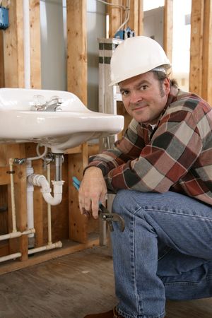 A friendly plumber installing bathroom fixtures on a construction site.の写真素材
