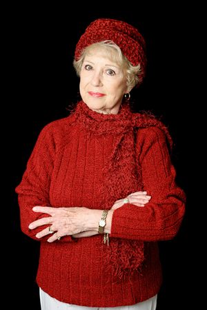 A three quarter view of a pretty senior lady in red winter clothing.  Isolated on black.の写真素材