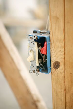 Closeup of an electrical switch box nailed to a wood beam on a construction site.  Shallow depth of field with focus on switch. Room for Textの写真素材