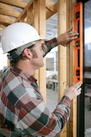 A construction worker checking that a newly installed window is level.  Vertical view.  Authentic...