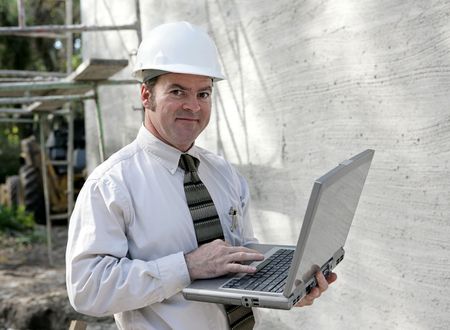 An engineer or building inspector checking building specs on his laptop computer.  
