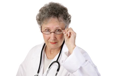 A mature female doctor staring seriously over her glasses.  White background.の写真素材