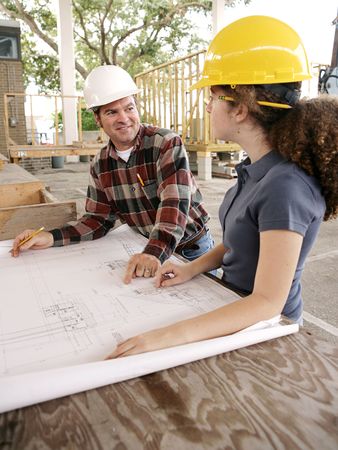 A construction foreman teaching a female apprentice how to read blueprints.  の写真素材