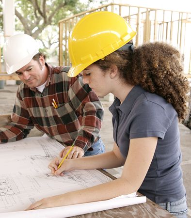 A female engineering student on a construction site marking blueprints as her instructor watches.  の写真素材