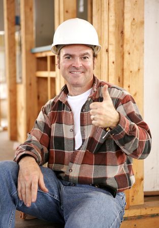 A handsome construction worker giving a thumbsup sign.  Authentic construction worker on actual construction site.  の写真素材