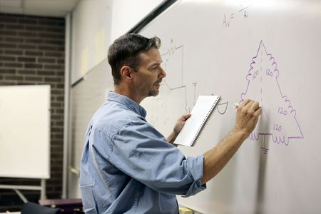 A handsome teacher drawing electrical circuit on a whiteboard.  