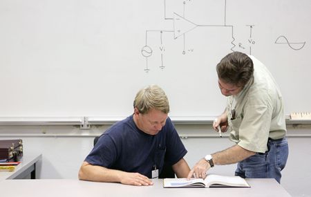 A middle aged adult education student getting help from his teacher.  の写真素材
