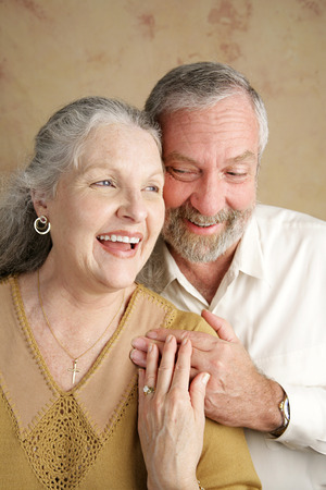 A beautiful gray haired couple in their sixties laughing together.  Focus on wife.の写真素材