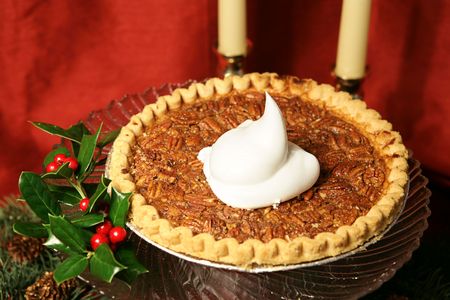 A delicious pecan pie garnished with holly and a dollop of whipped cream, photographed against a draped red silk background.  の写真素材