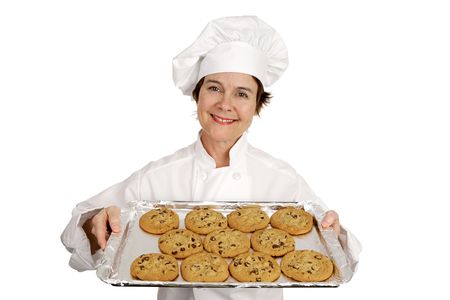 Pretty female chef holding a tray of freshly baked chocolate chip cookies.  Isolated on white.の写真素材