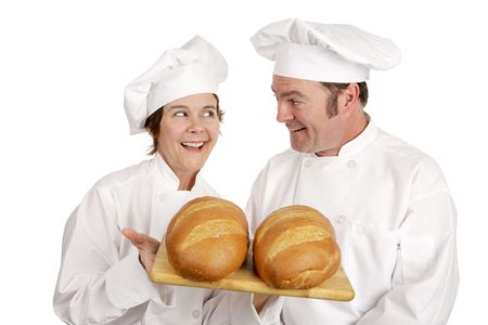 A male and female chef admiring two freshly baked loaves of bread.  Isolated on white.  の写真素材