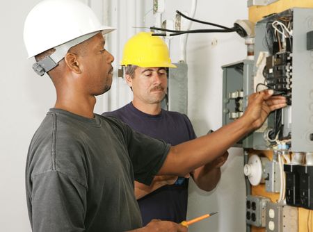 An african american and a caucasian electrician working on a panel.  Actual electricians performing work according to industry safety and code standards.  の写真素材
