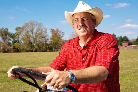 Handsome mature cowboy at the wheel of his tractor.の写真素材