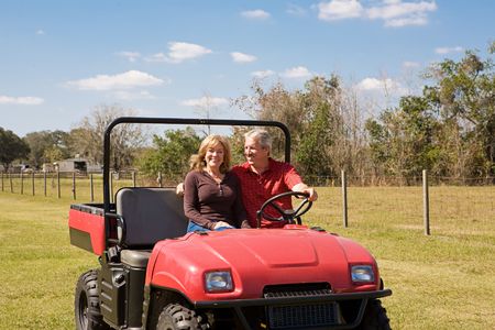 Beautiful mature couple having fun riding the farm in their all terrain vehicle.  Wide view with room for text.  の写真素材