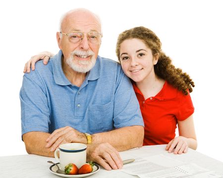 Teen girl and her grandfather at the table filling out paperwork together.  Isolated on white.の写真素材