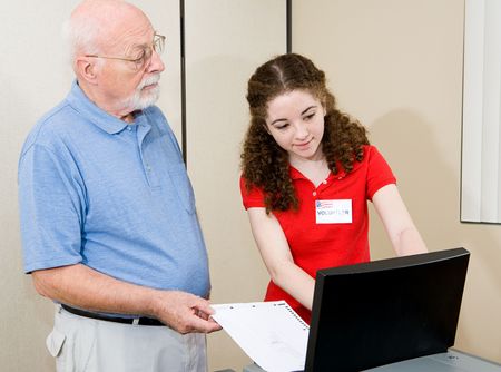 Teen volunteer helping senior voter use the new equipment on election day.  の写真素材