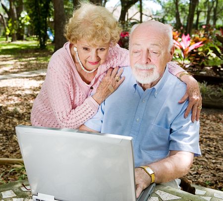Senior couple enjoys using their computer outdoors.  の写真素材