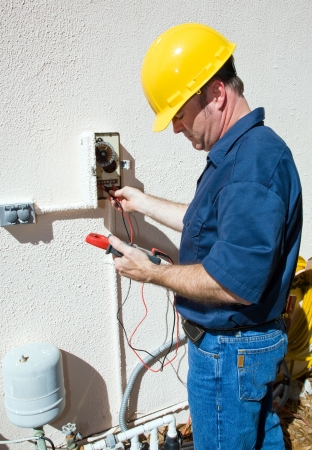 Electrician repairing a sprinkler pump, testing to see if it's receiving power.  Focus on model.  Model is a licensed electrician, working in compliance with national code and safety regulations.  の写真素材