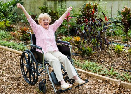 Beautiful senior lady in wheelchair is overjoyed because she has triumphed over her health problems.  の写真素材