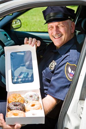 Police officer sitting in his squad car with a box of donuts.  の写真素材