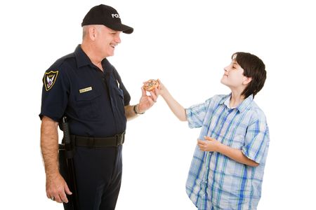 Adolescent boy giving a donut to a police officer.  Isolated on white.の写真素材