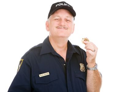 Police officer enjoys finishing off a donut.  Isolated on white.  の写真素材