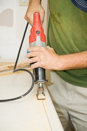 Contractor cutting through laminate counter top with a reciprocating saw.  Focus on the saw.の写真素材