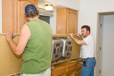 Carpenters installing a new laminate kitchen counter top and sink.  Focus on the man on the right facing camera.の写真素材