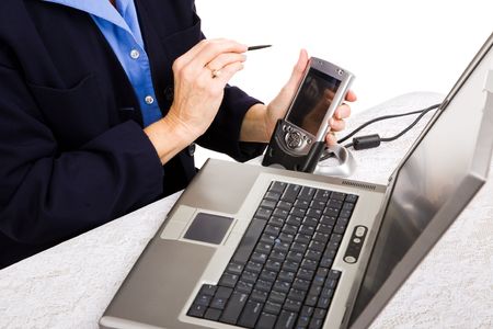 Closeup of a businesswoman transferring data from her PDA to her laptop.の写真素材