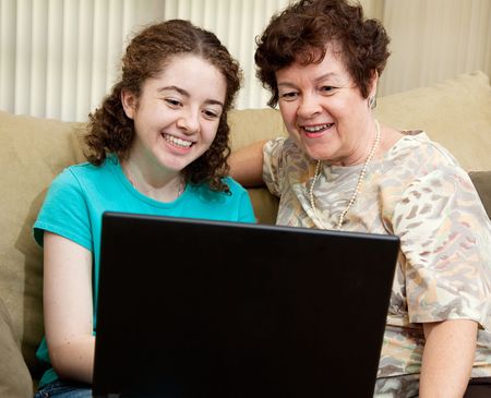 Teen girl and her mother enjoy using a laptop computer.  