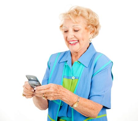 Senior woman enjoys texting on her new cellphone.  Isolated on white.  の写真素材