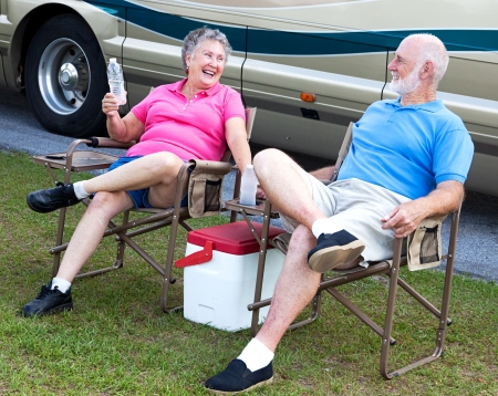 Senior campers sitting in folding chairs outside their motor home.  の写真素材