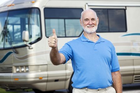 Senior man in front of his luxury motor home gives the thumbs up sign.  の写真素材