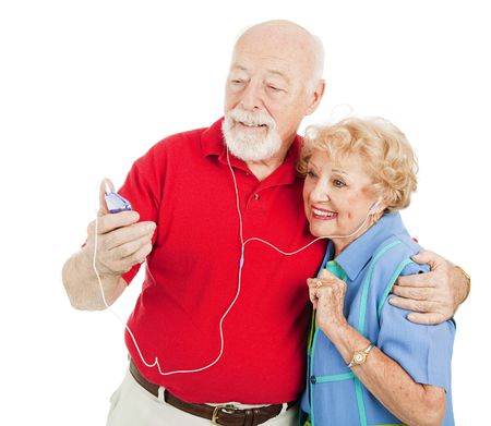 Tech savvy senior couple listens to mp3s on their media player.  Isolated on white.の写真素材