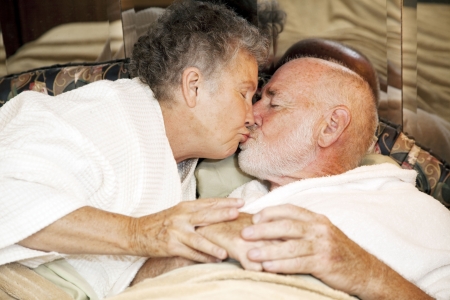 Romantic senior couple in bed kissing goodnight.  の写真素材