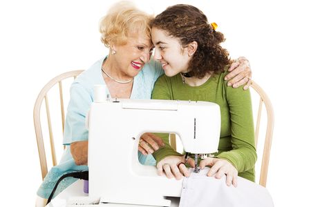 Grandmother teaches her teen granddaughter how to sew.  Isolated on white.  の写真素材