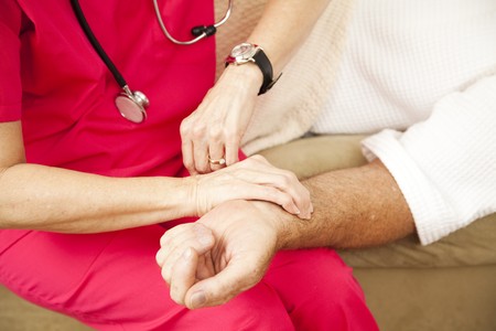 Closeup of a home health nurse's hands taking an elderly patient's pulse.  の写真素材