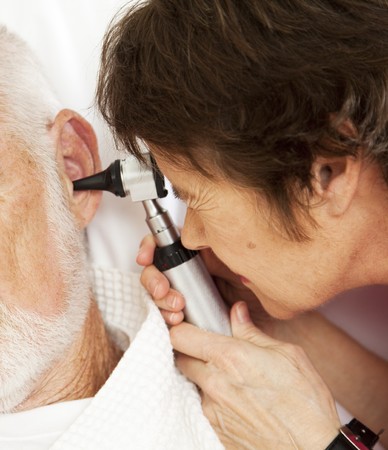 Closeup of nurse or doctor looking in a patient's ears with an otoscope.  の写真素材