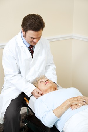 Senior woman gets her neck adjusted by a caring chiropractor.  の写真素材